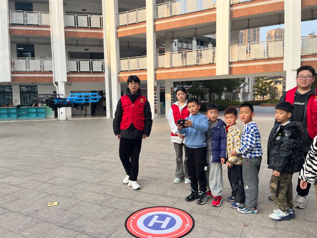 大学生志愿者指导小学生操作无人机.jpg